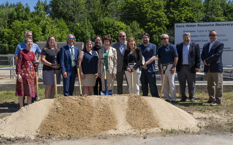 People stand in a line with shovels for the Saco treatment plant groundbteaking.