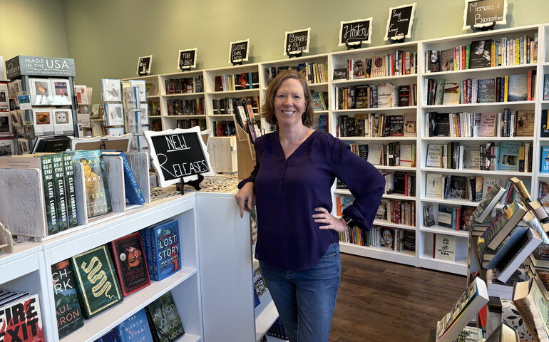 Bookstore owner with shelves of books.