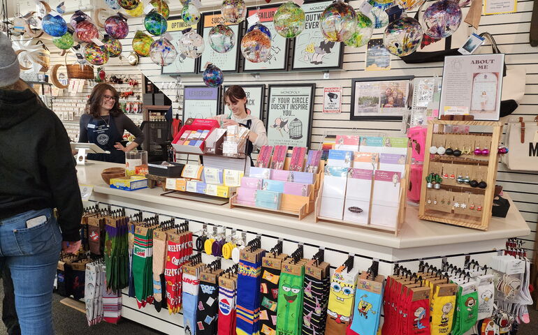 Clerks and a customer are inside a store with colorful products.
