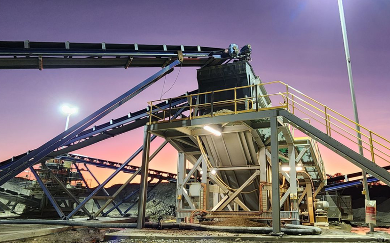 Mining equipment is seen against a colorful sky.