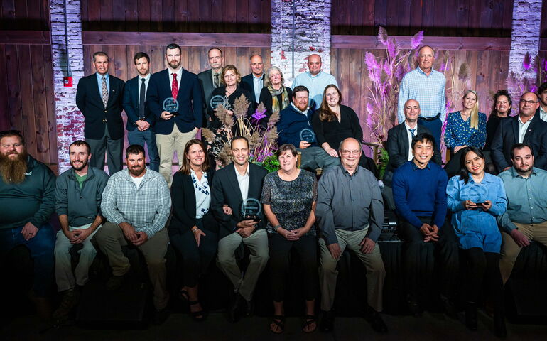 People pose against paneled background.