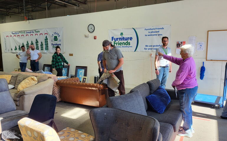 People are in a warehouse loading furniture.