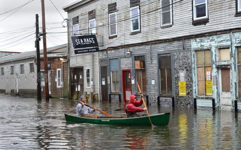 A flooded street and people paddling.