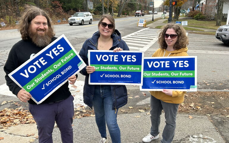Three people in Cape Elizabeth holding signs for school referendum.