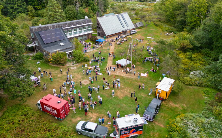 An aerial view shows a bunch of people and vehicles in a field.