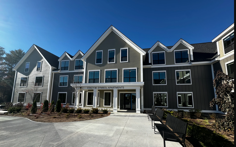 An apartment buildng with park benches.