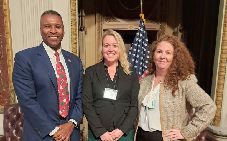 Three people pose at the White House.