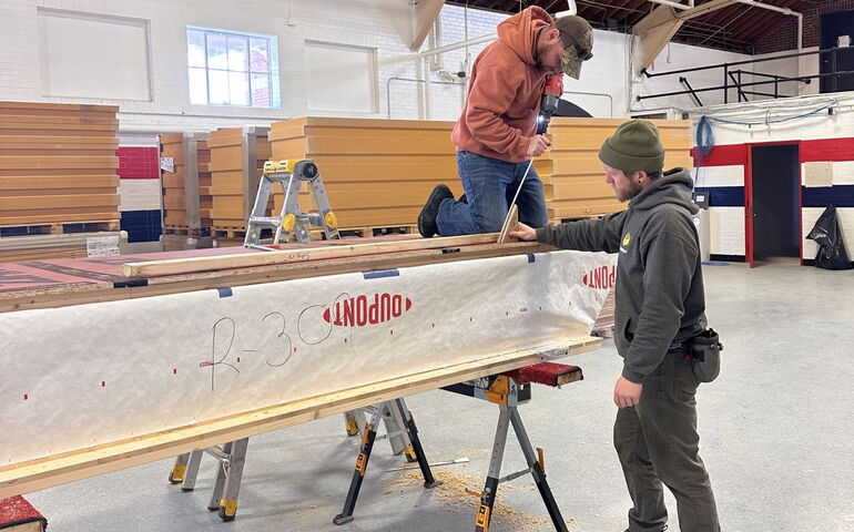 Two people work with a wood construction.