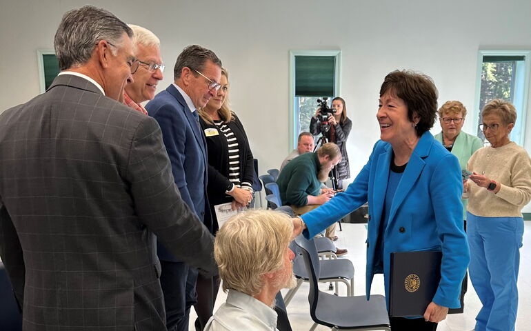 People gather in a classroom and shake hands.