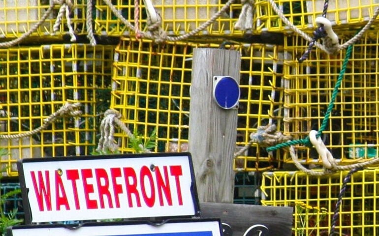 A sign is in front of stacks of lobster traps.
