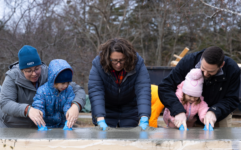 Five people pose ewith a cement slab.