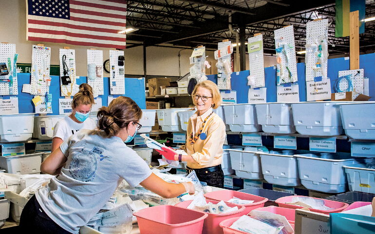 Elizabeth McLellan of Partners for World Health with volunteers in sorting warehouse.