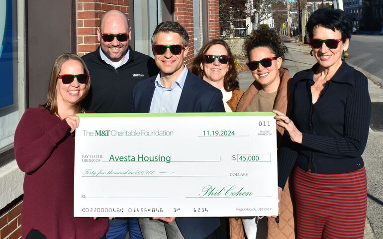 People stand on a sidewalk and hold an oversize check.