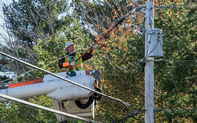 An line worker is in a bucket working on lines.