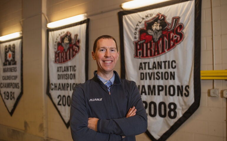 Greg Glynn of Pliable Marketing standing in front of Portland Pirates banners