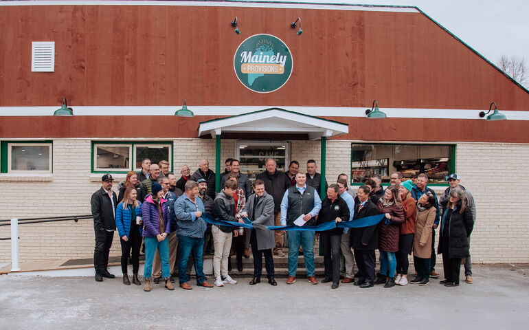 A group of people pose in front of a building with a ribbon.