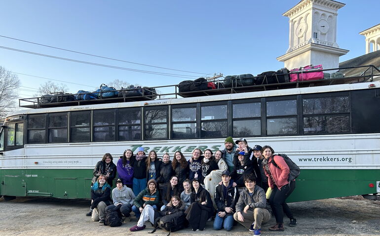 A group of people pose outside of a bus.