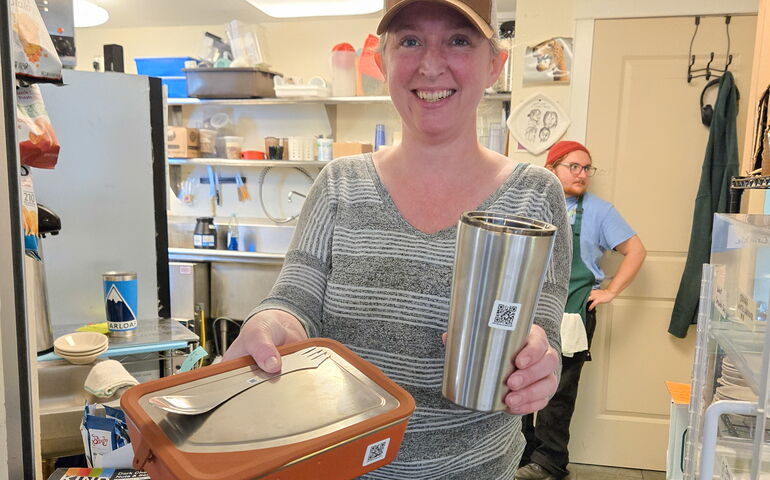 A person in a kitchen proffers containers.