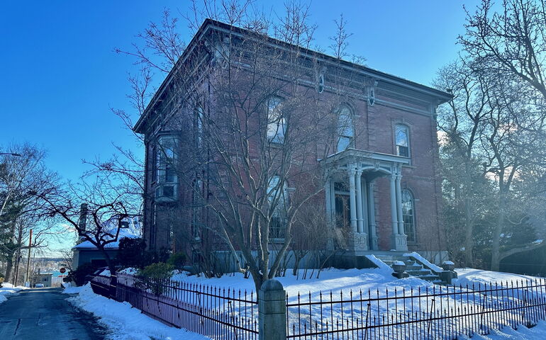 An exterior photo of a brick house ewith a metal fence.
