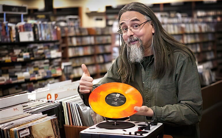 Chris Brown in a Bull Moose store holding an orange vinyl record 