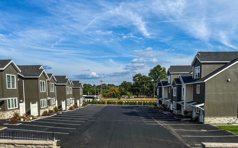 Two-story buildings line a parking lot.