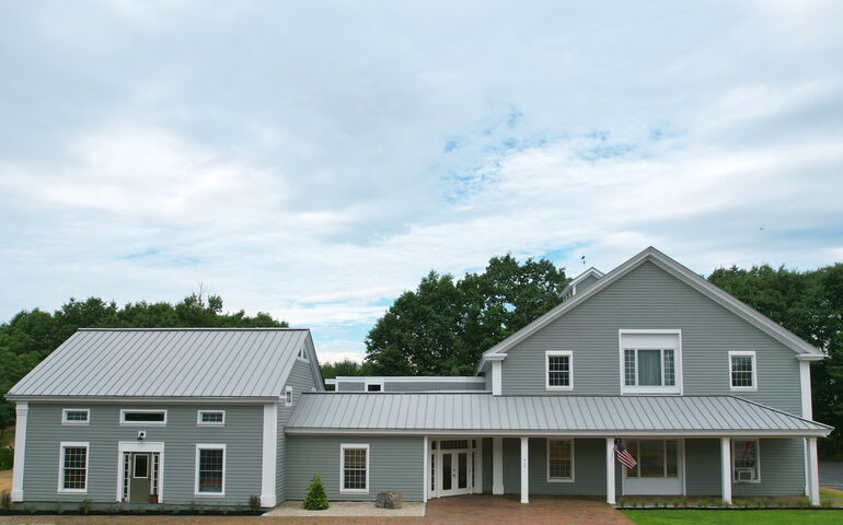 An exterior view shows a gray building with different wings and white trim.