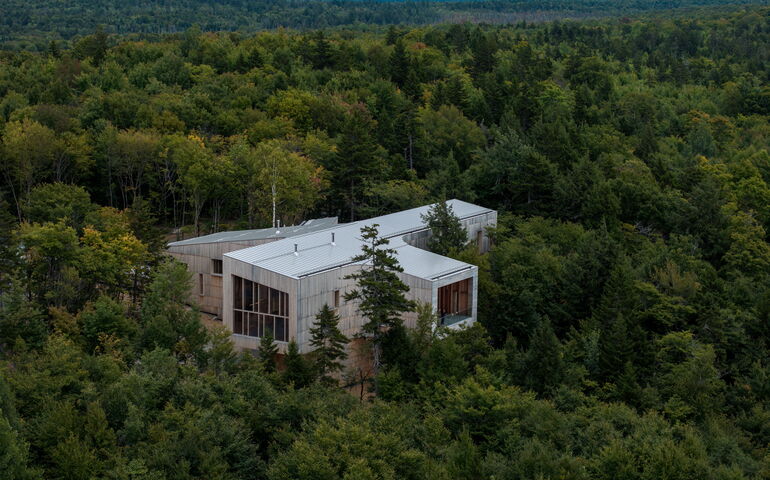 An aerial view of a boxy building in the woods.
