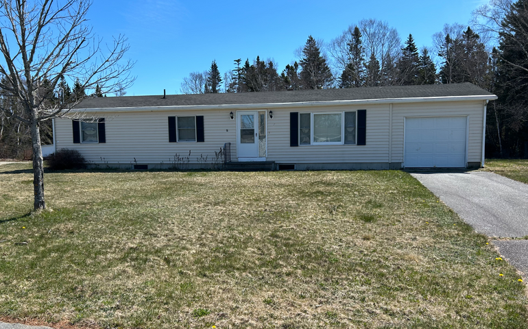 An exterior shot of a ranch house and lawn.