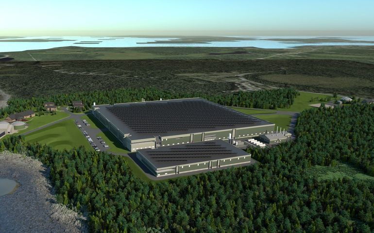 Aerial view of a large, flat, square building surrounded by woods.