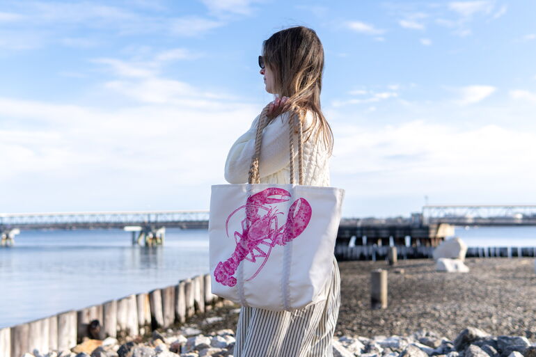 Woman holding a Sea Bag tote with pink lobster design