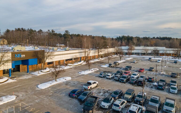 An aerial view of a shoping center with parking lot full of cars.