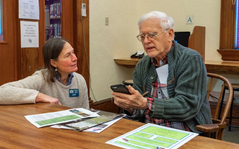 A person helps another person with a cellphone.