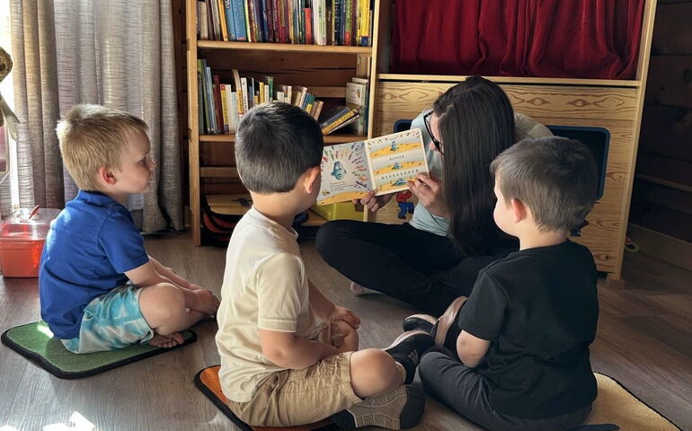 four people sit in a circle reading a book.