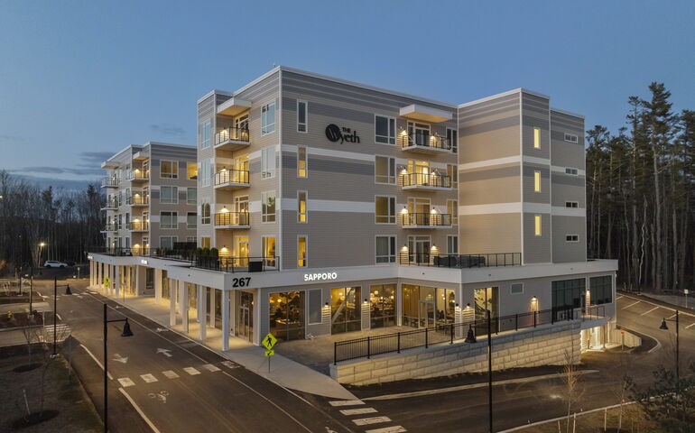 An exterior view shows a multi-story building with driveways around it.