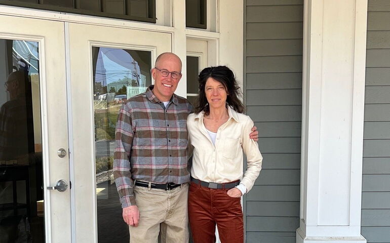Two people pose in an entryway.