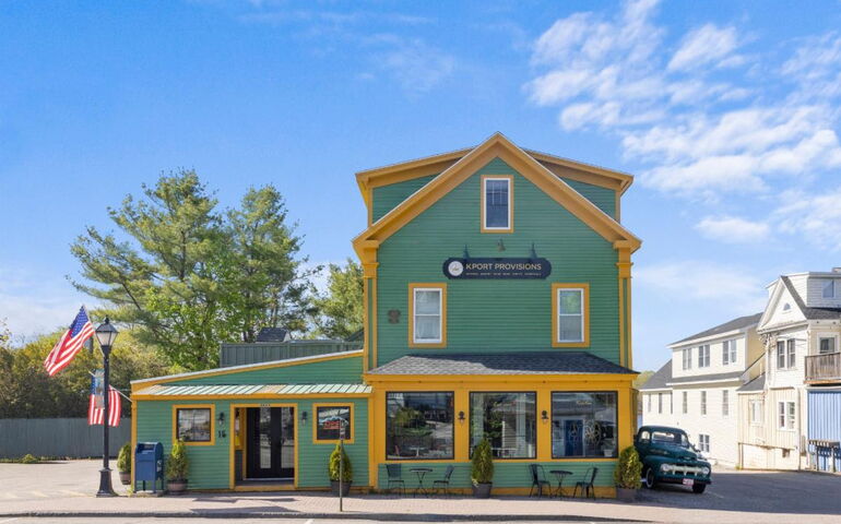 An exterior view of a green-sided building with mustard colored trim.