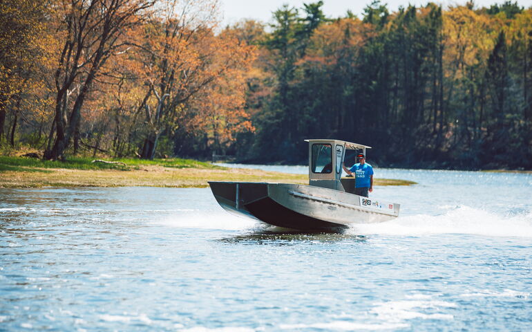 A metal boat runs on the water.