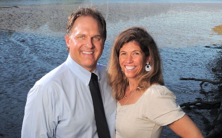 Two people pose by the water.
