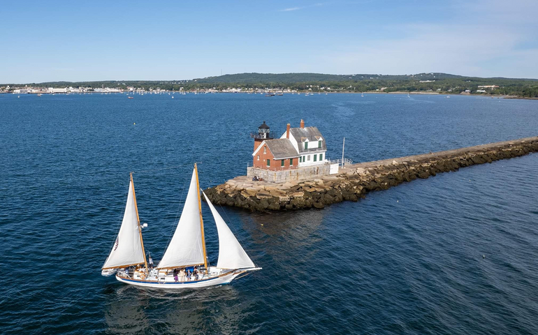 An aerial view of water and a sailboat.