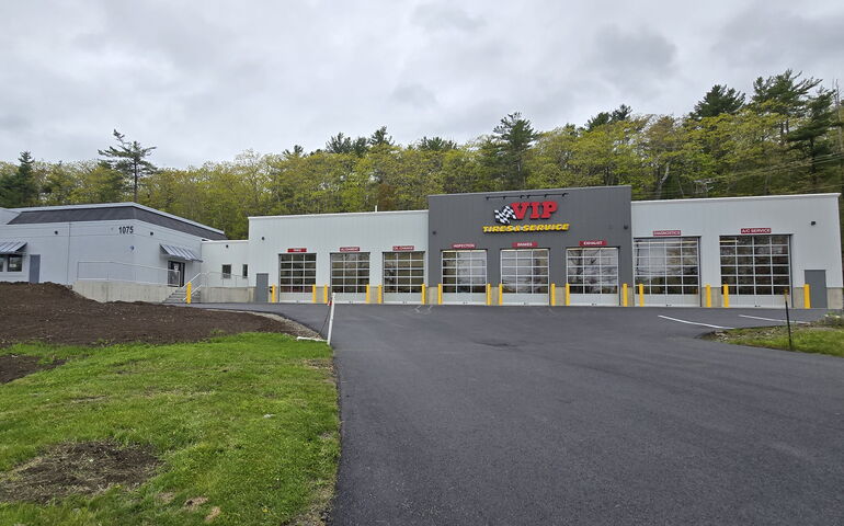 An exterior view of a building and drivway and lawn.
