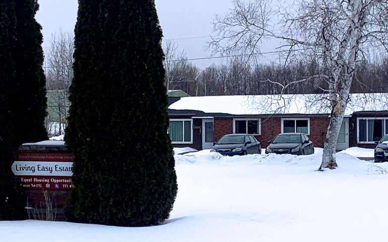 A building in the background has snow in front.