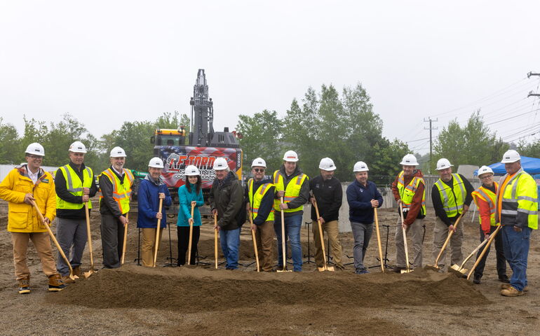 People line up with shovels at a pile of dirt.