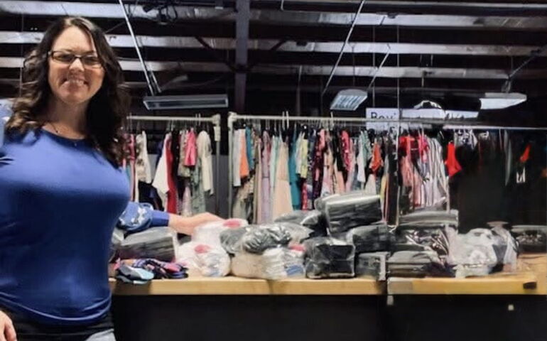 A person stands near a table rack loaded with clothes.