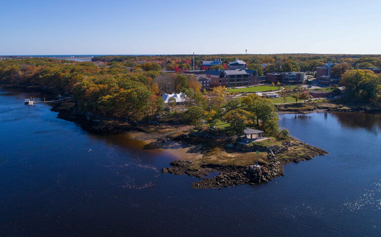 An aerial view of buildings, woods and water