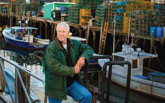 A person stands on a dock  with boats behind.