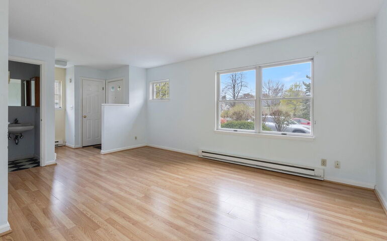 An empty room has white walls and wood floors.