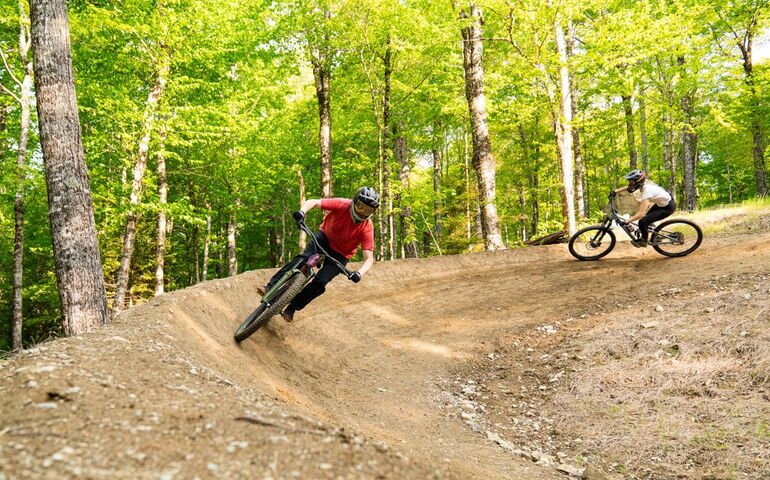 Two people rike bikes on a trail.