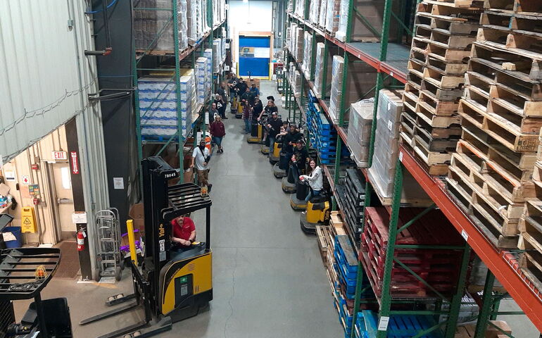 People gather inside a warehouse full of shelving.