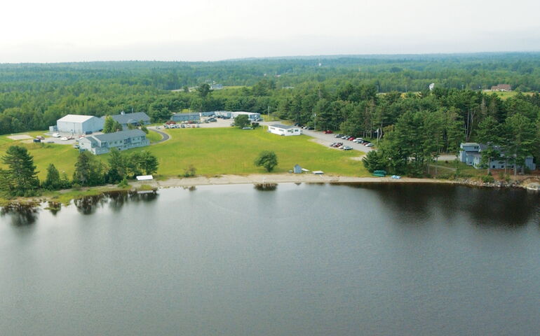 An aerial view of buldings surrounded by lawns, water and trees.