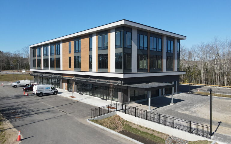 An exterior view shows a blocky building and a parking lot.